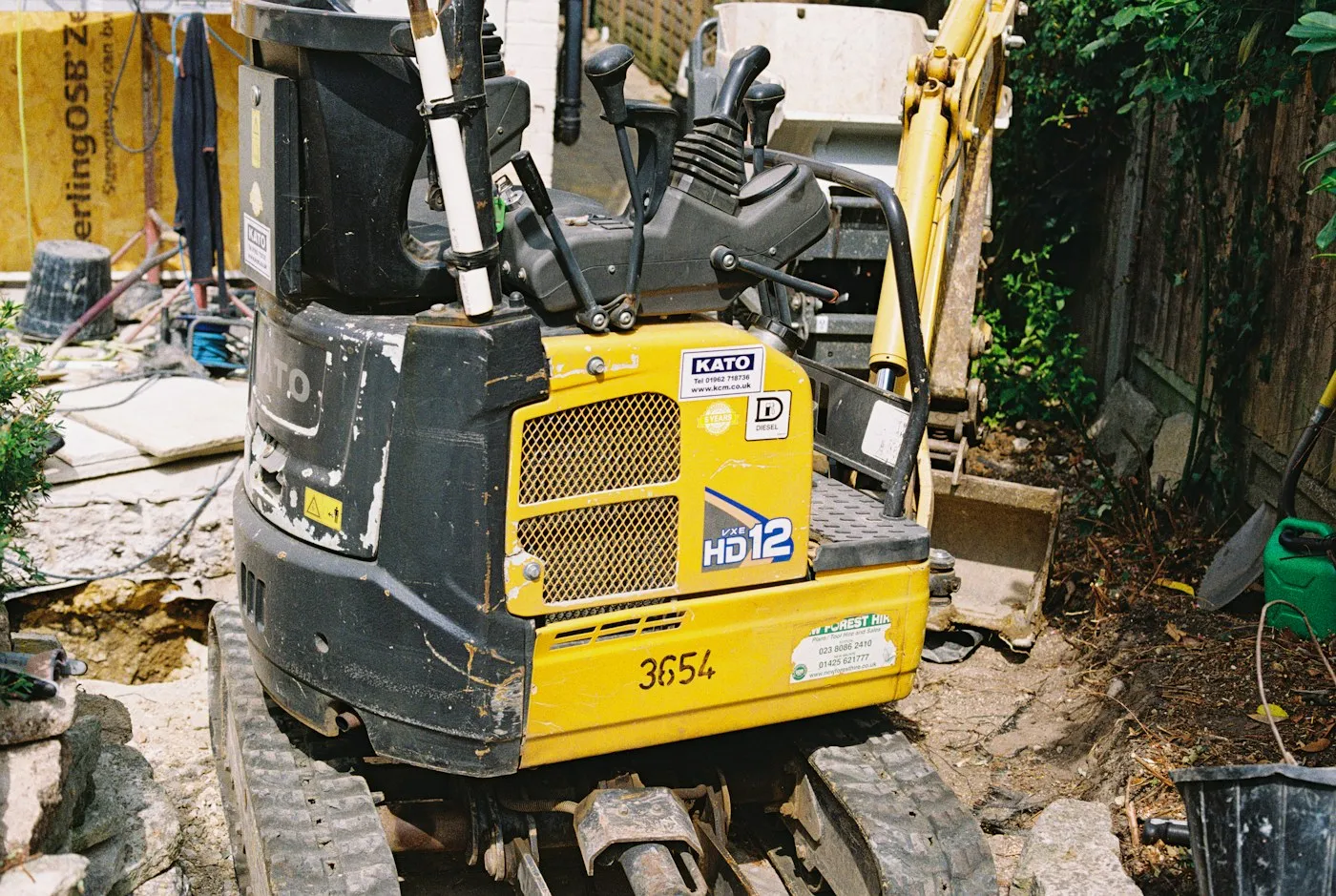 Rear view of a compact excavator beside a structure